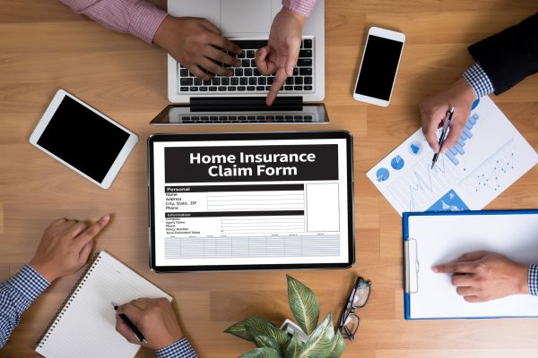 Home Insurance Claim Form Document Refund Home Insurance Business team hands at work with financial reports and a laptop, top view
